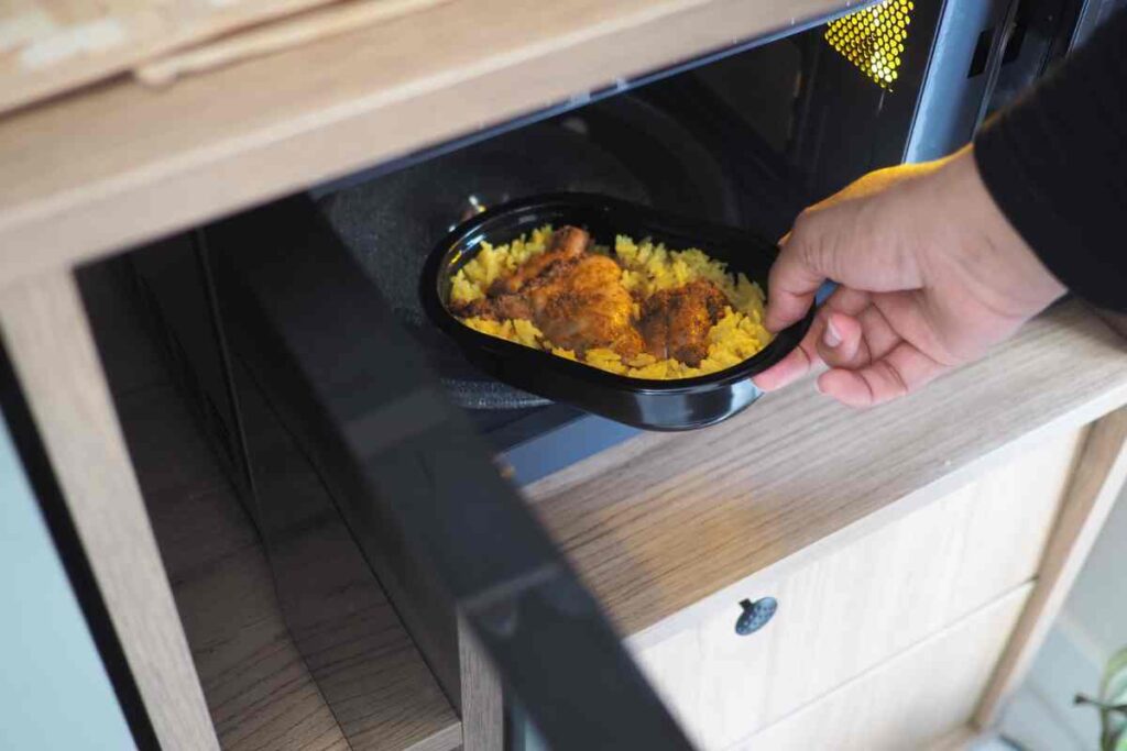 mano mette piatto di plastica con cibo in microonde