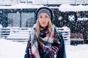 donna sotto la neve che indossa sciarpa e cappuccio