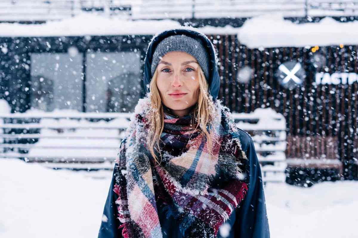 donna sotto la neve che indossa sciarpa e cappuccio