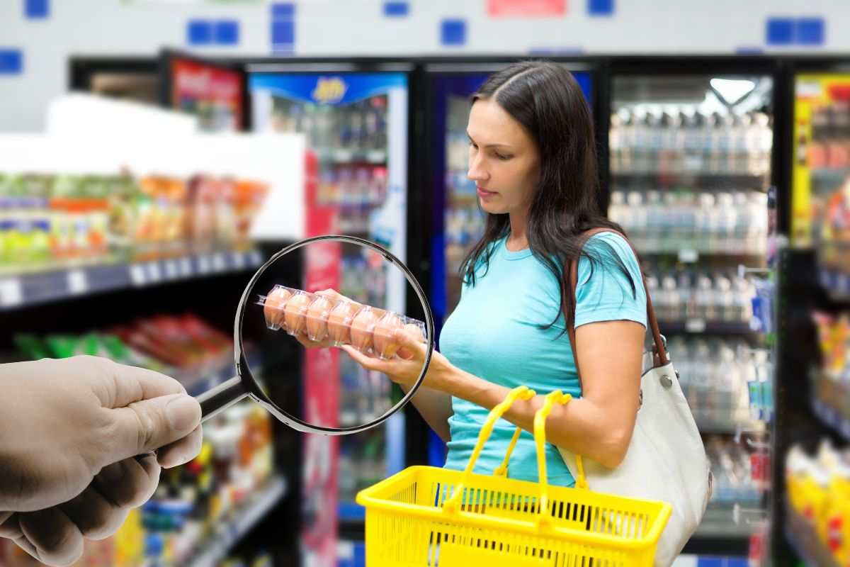 donna al supermercato con uova in mano e lente d'ingrandimento
