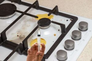 piano cottura sporco e mano che mantiene siringa