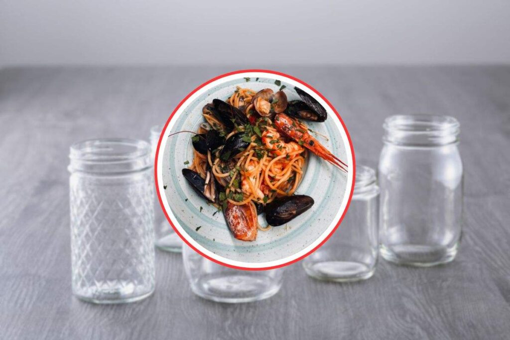 sfondo in cui si vedono dei barattoli di vetro e in primo piano uno spaghetto allo scoglio