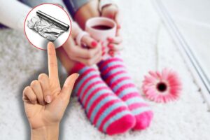 donna con calzini di pile ai piedi e tazza in mano, indice che indica carta stagnola in icona rossa