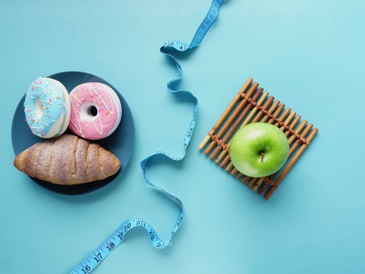 ciambelle e cornetto in un piatto posto su un tavolo con accanto un piatto con una mela verde