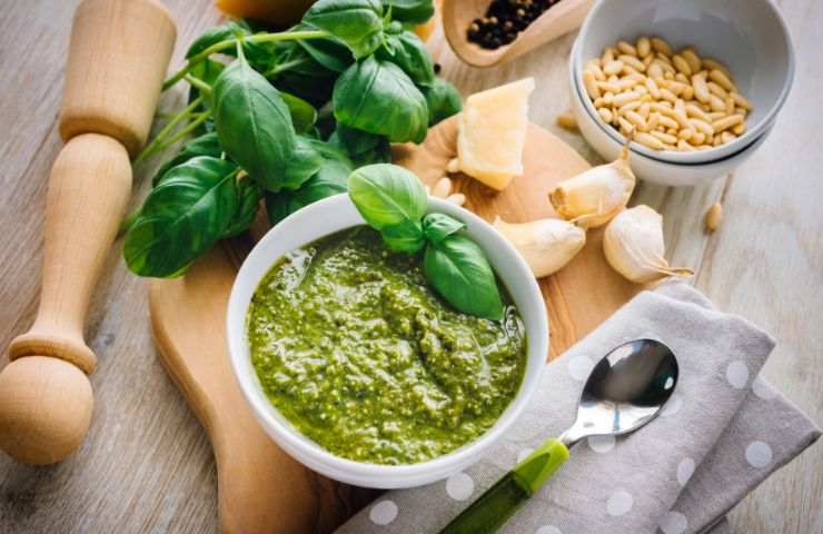 pesto alla genovese su tagliere con aglio, basilico, formaggio e pinoli