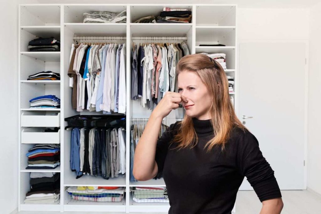 donna che si tappa il naso per il cattivo odore che esce dall'armadio