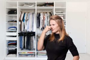 donna che si tappa il naso per il cattivo odore che esce dall'armadio
