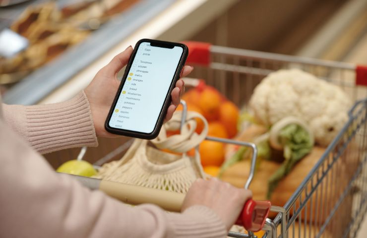 donna con lista spesa su smartphone