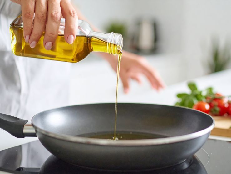 olio d'oliva che viene versato in una padella su un piano cottura