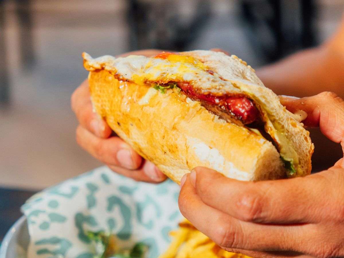 persona tiene in mano un panino imbottito