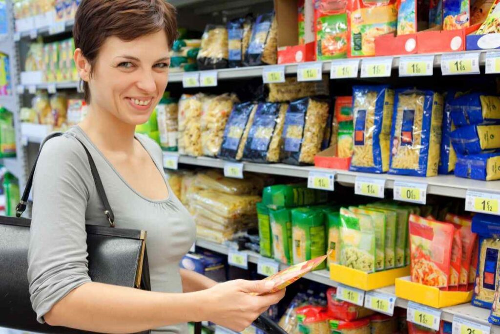 donna sorridente al supermercato che sceglie pasta