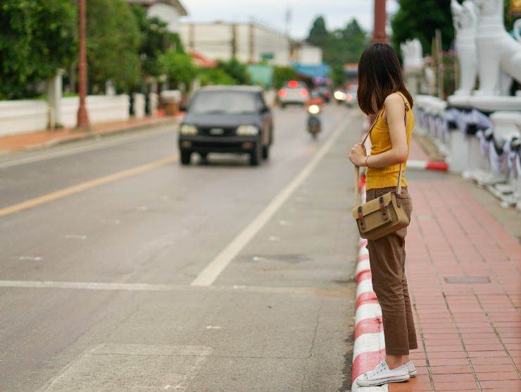 ragazza sul ciglio della strada che aspetta per attraversare