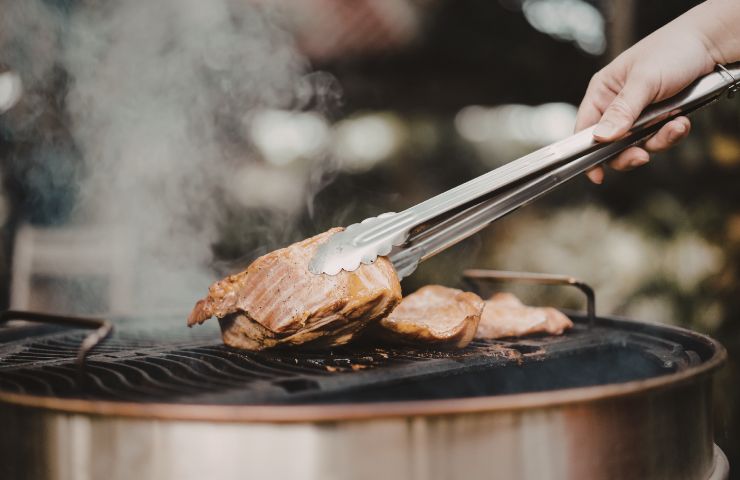 donna che cuoce carne alla griglia
